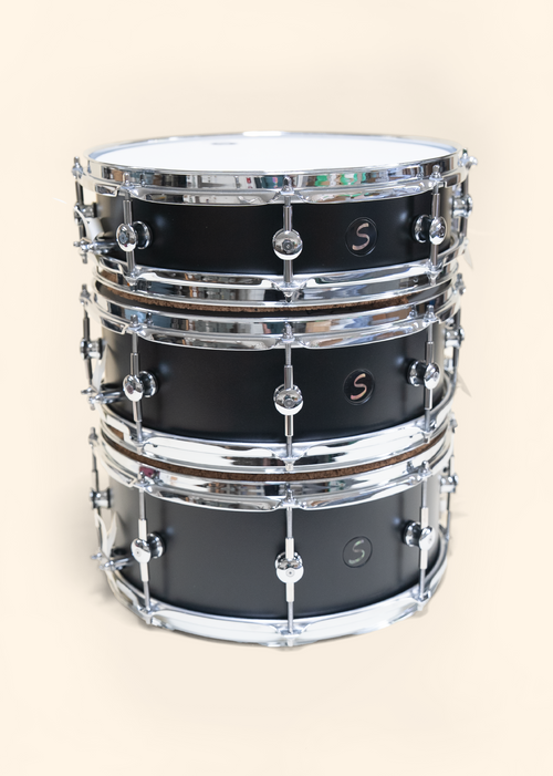 Black painted Poplar drums with clear matte finish. Ebony badges with black pearl inlay.  Three different sizes with two hoops options.